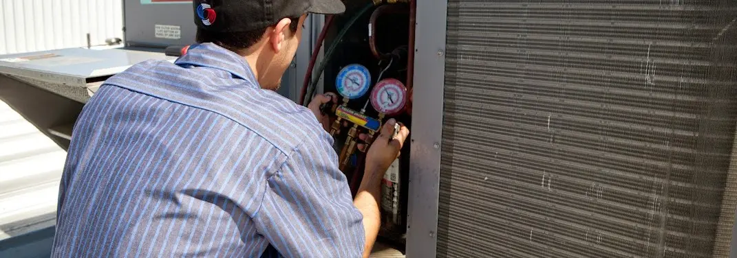 HVAC technician servicing a condenser unit in Rock Falls